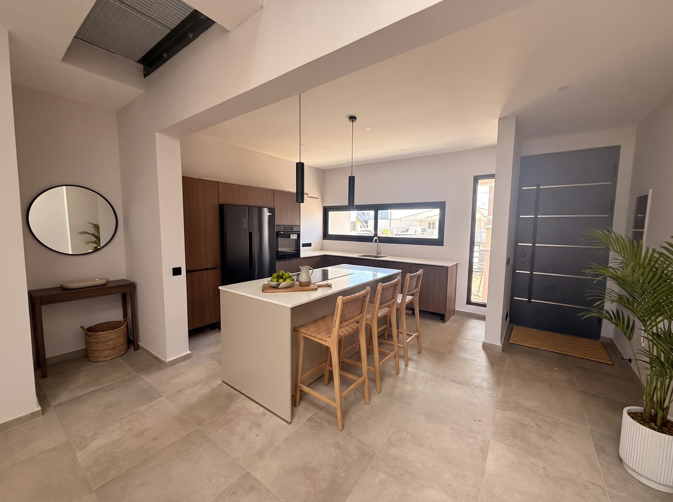 Kitchen with island and bar stools, front door to the right
