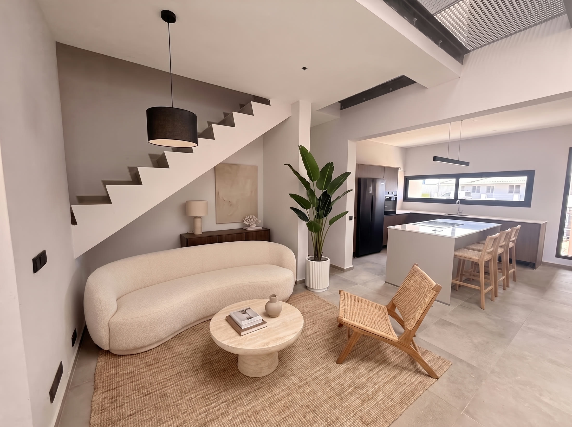 Living room with open concrete stair and kitchen island beyond