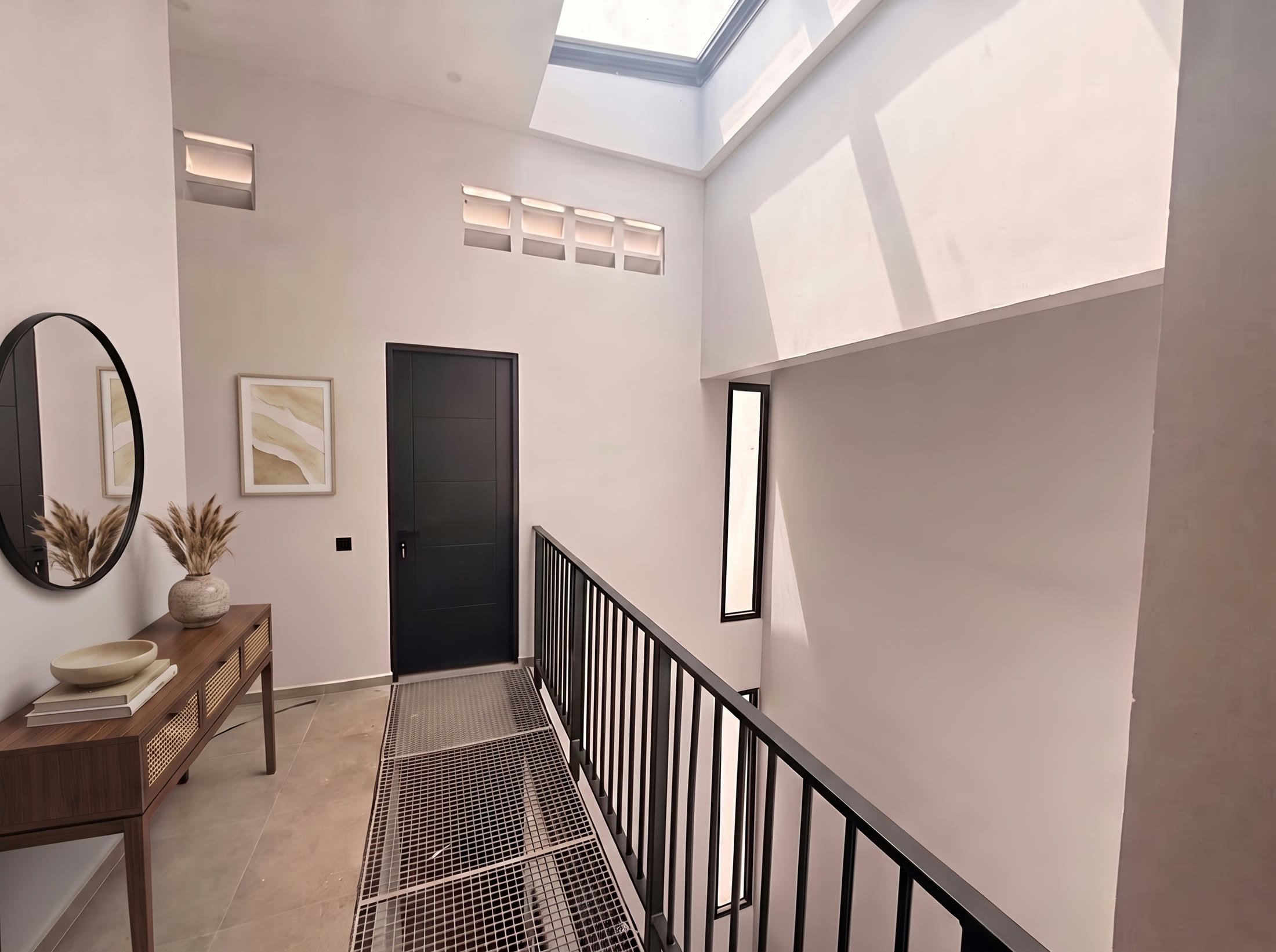 Upstairs landing with console table and round mirror under a skylight