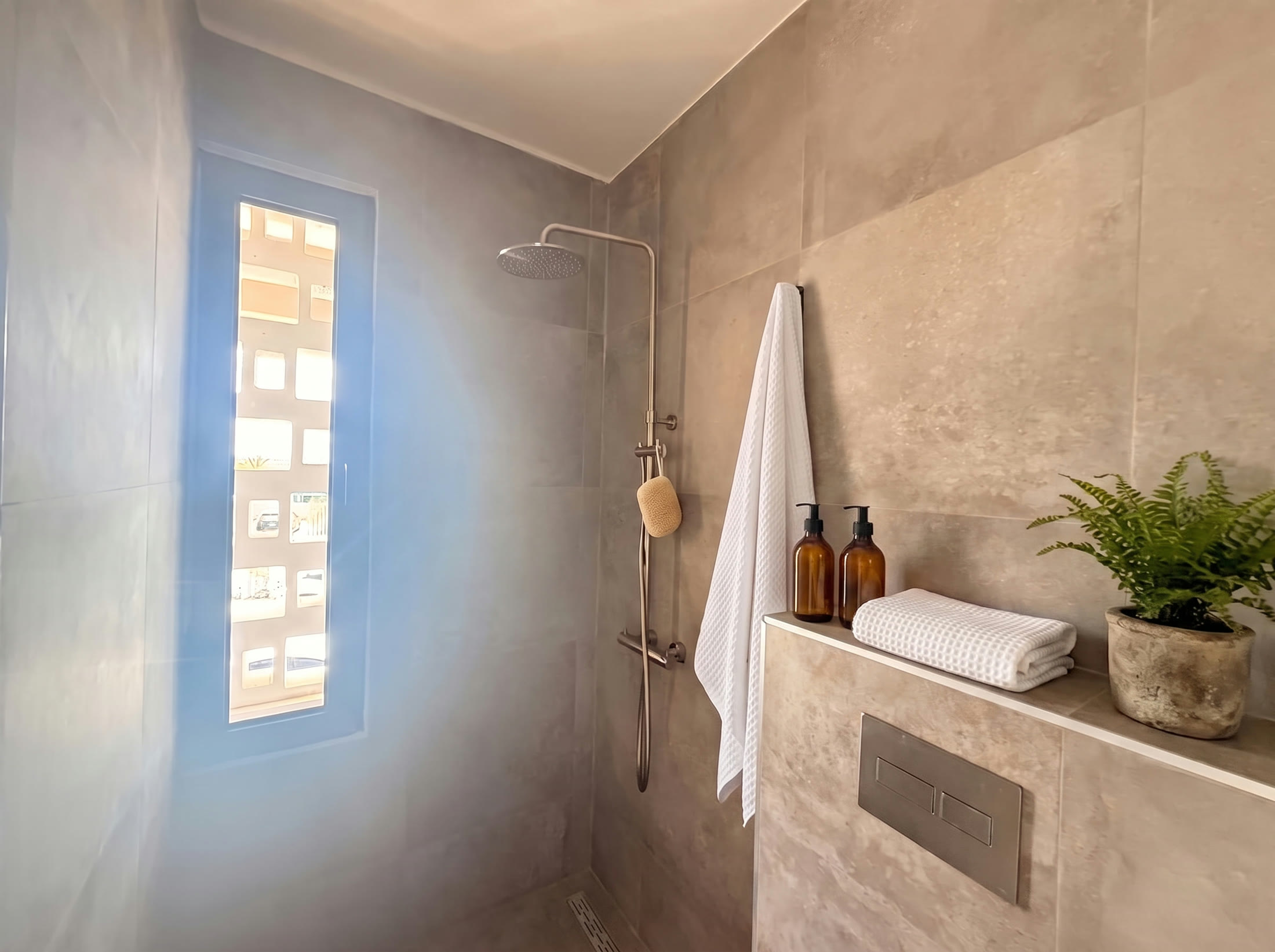 Tiled walk-in shower with rain head and tall narrow window